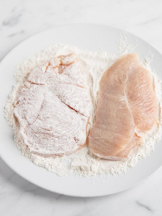 Chicken dredged in flour on a plate.