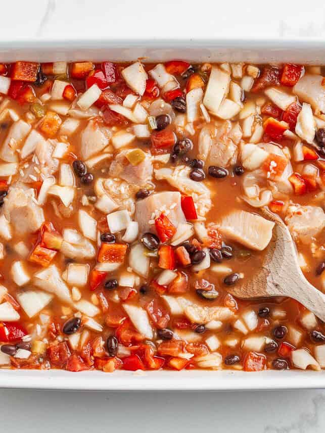 Stirring Mexican chicken and rice bake together before baking.