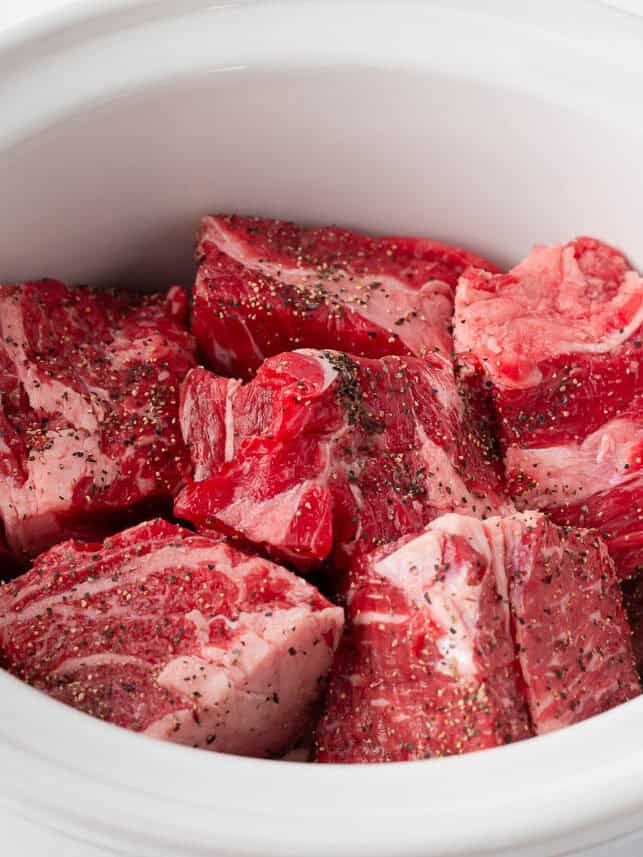 Beef chuck roast in a white crockpot.