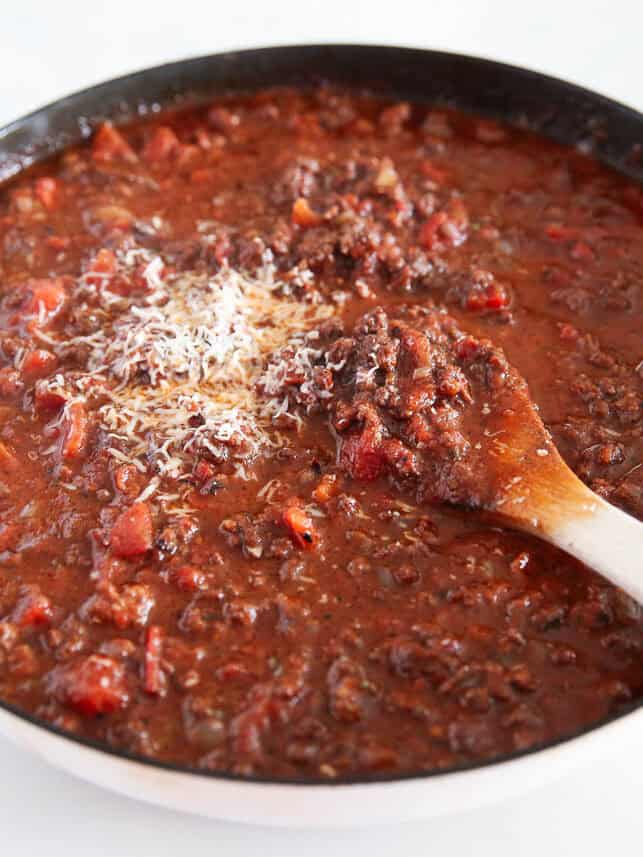 Bolognese sauce simmering in a large skillet.