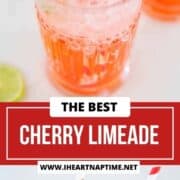 Cherry limeade in a glass garnished with cherry, lime and straw.