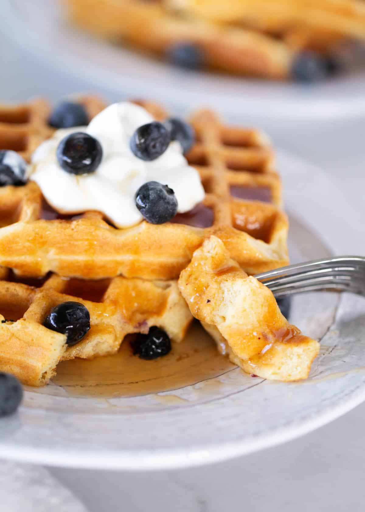 Bite of sourdough waffles with syrup and blueberries.