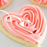 A heart shaped cookie with pink frosting for Valentine's Day.